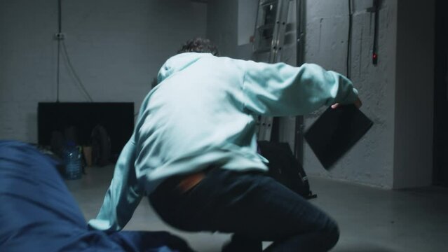 Tracking handheld shot of web developers while working in a bomb shelter during the war, hearing an explosion and a bomb attack nearby and running to the wall