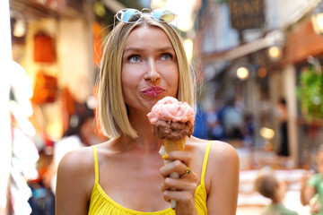 Young happy woman eating ice cream in cone while sightseeing Venice , Italy. Real people emotions....
