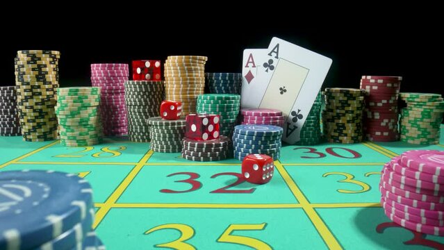 Set of colorful chips, playing cards and red dice on a gaming table for gambling in a casino. Dice falling on the table close up in slow motion. Poker set on a black background.