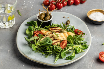 Fresh salad with grilled halloumi cheese, tomatoes, capers, lettuce and arugula. ketogenic paleo diet. Delicious breakfast or snack, Clean eating, dieting, vegan food concept.