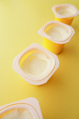 fresh yogurt in a plastic container and spoon on table 