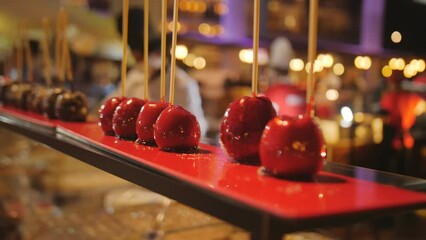 Rows of apples in sugar and chocolate syrup on a stick on a holiday.