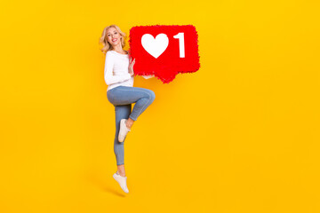 Full body photo of hooray young blond lady jump hold like wear shirt jeans sneakers isolated on yellow background