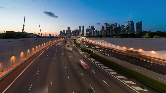 Day to night time-lapse car traffic transport on multiple lanes highway, financial district buildings, crane construction in Singapore. Asia transportation, commuter lifestyle, Asian city life concept