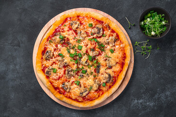 Italian pizza with vegetables, cheese and fresh herbs on a black background.