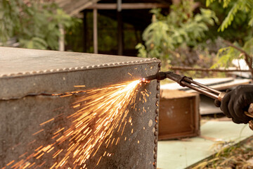 A factory worker cuts metal using an acetylene torch. Manual plasma cutting in a steel plant is...