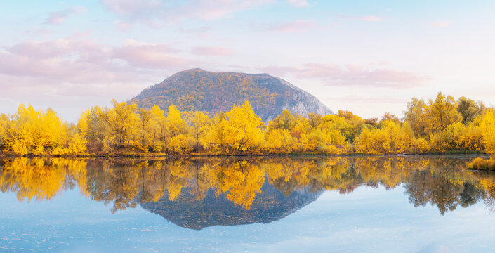 A good place for fishing and recreation. A picturesque pond in autumn with a lonely mountain in the background