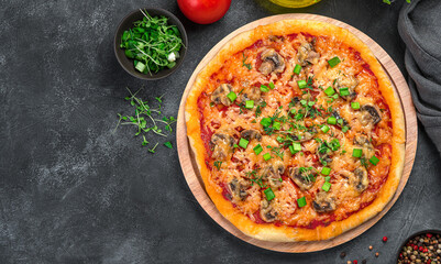 Pizza with vegetables and fresh herbs on a black background. Pizza with cheese, tomatoes and mushrooms on a thin dough.