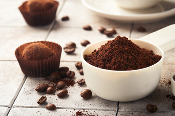 Coffee background. Measuring spoons with ground coffee, beans, cup and sweet chocolate truffles on old tile cracked table background. Food background. Top view with space for your text