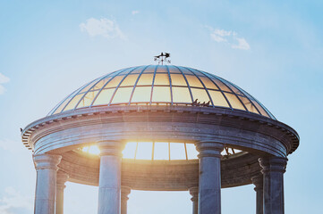 The transparent dome of the rotunda against a blue sky with clouds. Bright sun glare. Group of...
