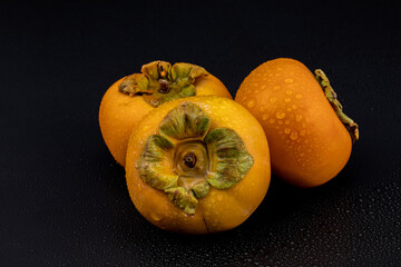 Persimmon - Fresh Kaka fruits isolated in extendable black background with shadow and water drops on it crystal clear macro details, shot using studio lights and macro lens.
