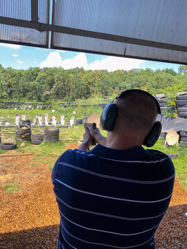 Man Firing Pistol At Target In Outdoor Shooting Range