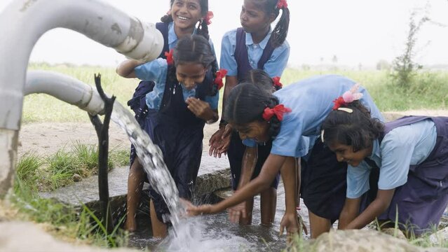 group of village school girl kids playing in water near paddy field - concept of happiness, fun and carefree lifestyle