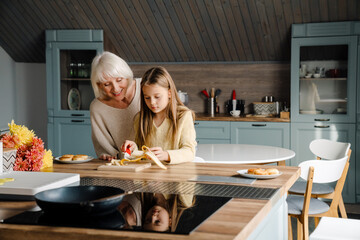 Happy grandmother and granddaughter cooking breakfast together
