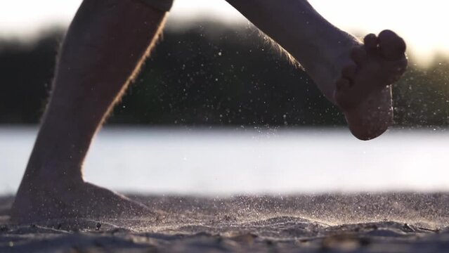 Close-up of Kicking Soccer Ball. Slow Motion. Man's Foot Kicks Ball Lying on Sand