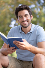 happy man reading a book outside in the park