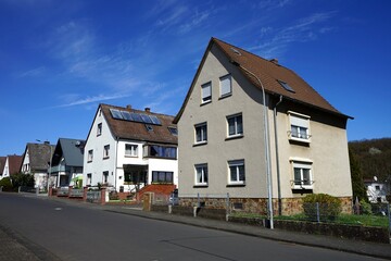 Häuserzeile mit alten Wohnhäusern mit Spitzgiebel in Weiß und Naturfarben vor blauem Himmel im...