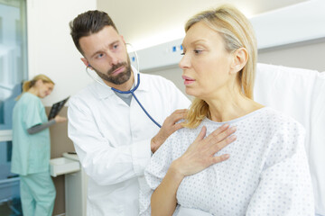Fototapeta premium doctor using stethoscope to examine anxious woman