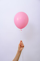 vertical one minimal pink balloon in hand on white background, copy space, element of decorations...