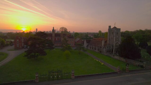 Aerial footage as drone rises over Carew Manor and St Mary&rsquo;s Church at beautiful sunrise with Croydon skyline on the background, UK