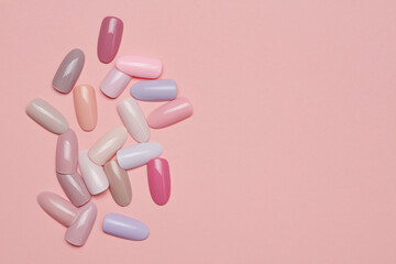 Testers nail polish of pastel colors on pink background. Set of false nails for manicure. Varnish color palette for nail painting. Palette for varnish. Selective focus.