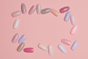 Frame of nail polish of pastel colors on pink paper or background. Testers nail polish of pastel colors on pink background. Set of false nails for manicure. Varnish color palette for nail painting. 