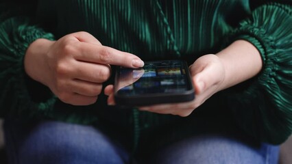 Woman touching scroll page app on mobile phone. Browsing movie video in the internet library to watch film online - Netflix, Megogo, Youtube, Amazon Prime, Hulu, Mubi.