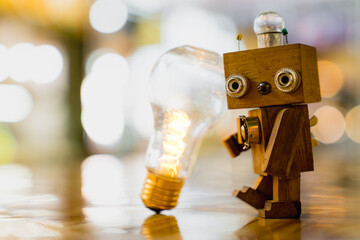 Retro wood robot hold light bulb with two hand with bokeh light background,, nature power energy...