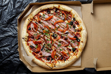 Pizza with sausages and red onion on a white background. Top view. pizza in a box on a black plastic background.