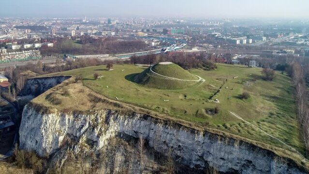 Krakus Mound in Krakow, Poland. The origin of the mound, probably early medieval kurgan, is not known. Old quarry in front. City panorama in the background. Aerial 4K video.