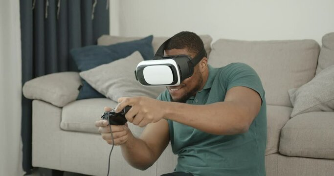 Black man in virtual reality glasses sitting on the carpet