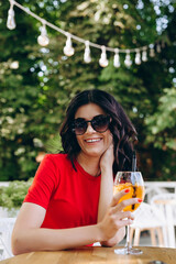 Beautiful smiling brunette with a cocktail in her hands enjoys a moment of relaxation in a cafe