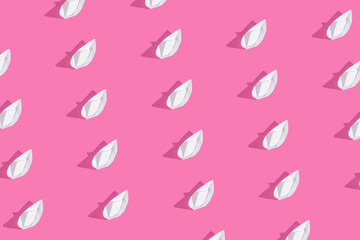 Creative pattern made of paper boats on bold pink background. Minimal summer concept. Flat lay...