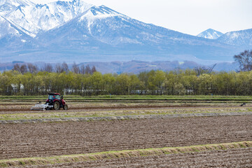 北の大地で広大な畑を力強く耕すトラクター
