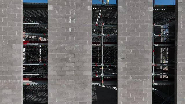 Close-up shot of the building under construction, camera is moving along the concrete wall.