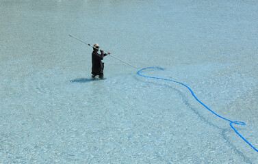 worker with a hose cleans the pool