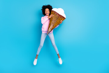 Full size photo of young girl have fun jump energetic holding big ice cream isolated over blue color background