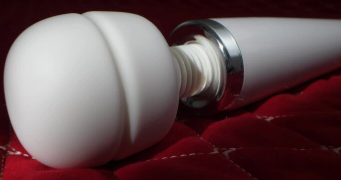 detailed, extreme close-up of a white vibrator on a red blanket