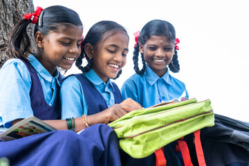 teenager school girl kids busy reading book while sitting under tree near paddy field - concept of knowledge, friendship and education.