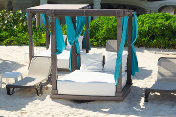 Comfortable sunbed on the private beach of a luxury hotel. Empty chaise-longues on the sandy beach. Beach holiday in comfort.