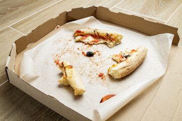 empty cardboard pizza box with pizza leftovers. After meal. Dirty dishes after dinner.