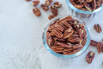 roasted pecan nut in glass bowl on white table background.