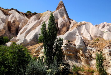 Landscape with a pyramid-shaped mountain and snow-white wavy mountains in the foreground in the Rose Valley between the towns of Goreme and Cavusin in Cappadocia, Turkey