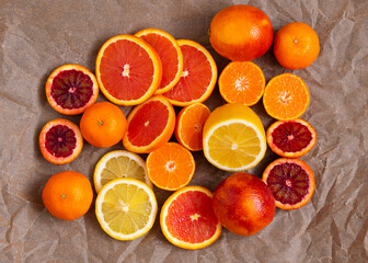 pieces of citrus fruits: orange, blood orange, lemon, tangerine on a background of crumpled craft...