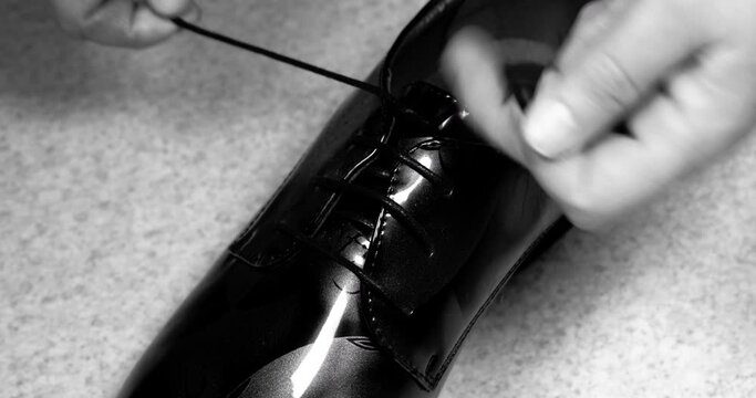 black and white hands tying shoelaces. tie his dress shoes. vintage video