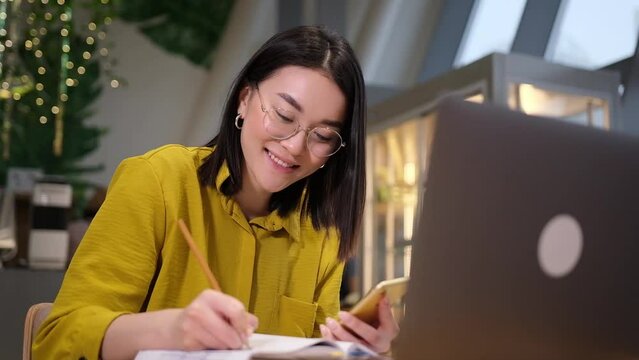Asian female sitting at workplace looking at laptop screen raising up her index finger feels happy and proud making right creative decision. Self-employed woman came up with great brilliant idea