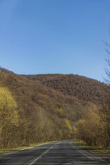 Blue sky above mountain forest and road in spring.