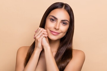 Portrait of attractive cheery long-haired girl enjoying smooth silky skin isolated over beige...