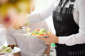 Waiter carrying plates with salad on some festive event, party or wedding reception. Staff of restaurant or cafe. - obrazy, fototapety, plakaty