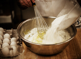 Baker mixing flour and eggs in a bakery